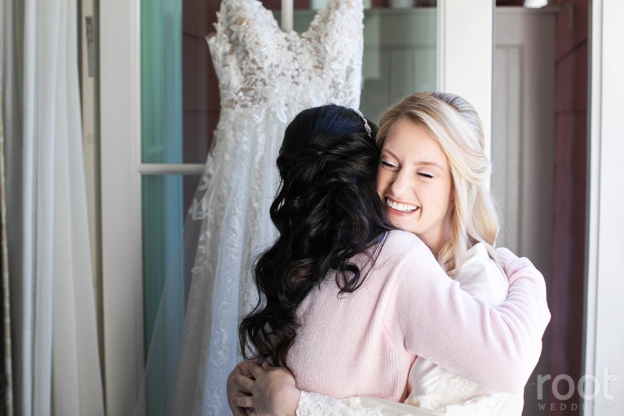 Mother of the bride hug in front of a wedding dress